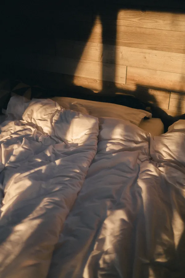 Morning sunlight falling across a rumpled bed