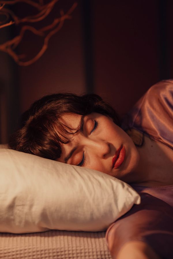 A woman sleeping peacefully on a pillow in a dim room
